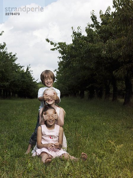 Drei Kinder spielen auf einem Feld