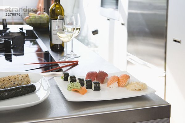 Sushi und Weißwein auf einer Küchenbank
