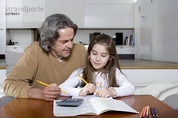 Ein Vater hilft seiner Tochter bei den Hausaufgaben.
