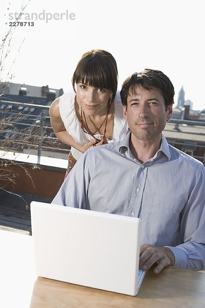 Zwei Personen mit einem Laptop auf der Terrasse