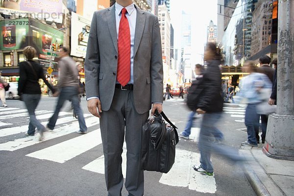 Ein Geschäftsmann  der an einem Fußgängerüberweg steht.