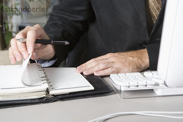 Detail eines Geschäftsmannes mit einem Terminplaner an seinem Schreibtisch