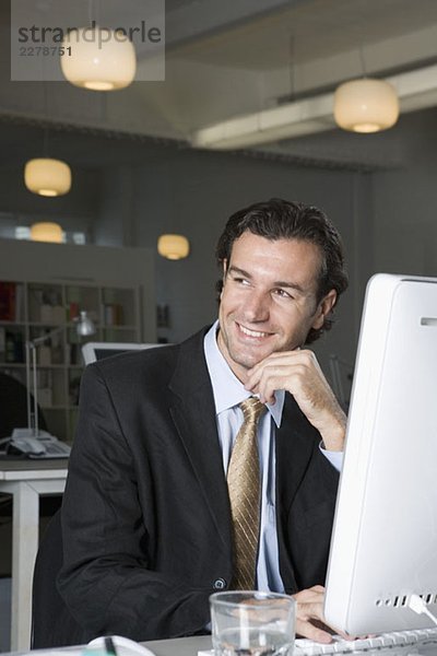 Ein Geschäftsmann  der an einem Computer in einem Büro sitzt.