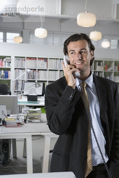 Ein Geschäftsmann  der ein Telefon in einem Büro benutzt.
