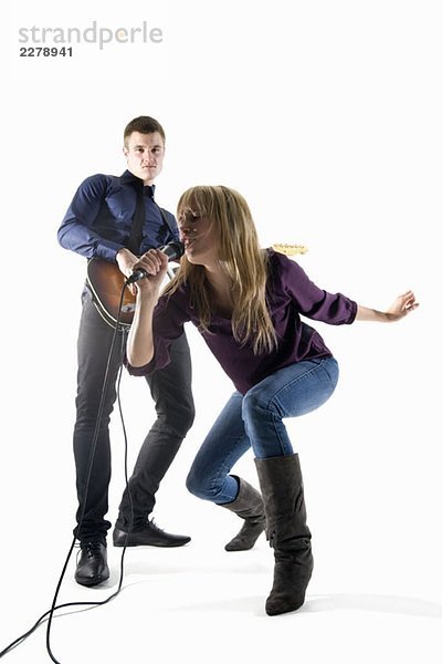 Studioaufnahme eines Mannes  der E-Gitarre spielt und einer Frau  die in ein Mikrofon singt.