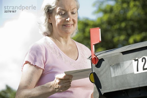 Eine ältere Frau  die den Briefkasten überprüft.