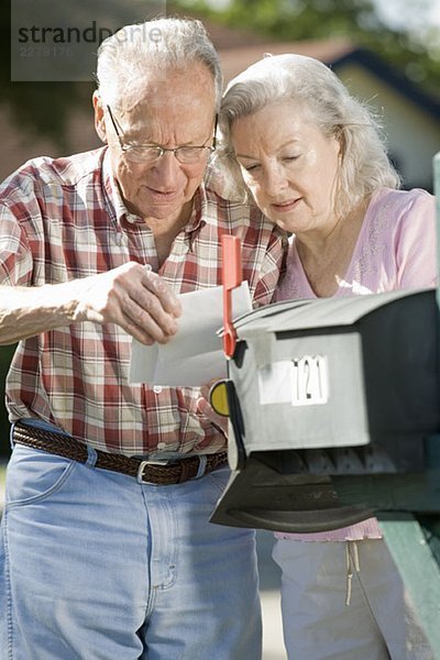 Ein älteres Ehepaar  das den Briefkasten überprüft.