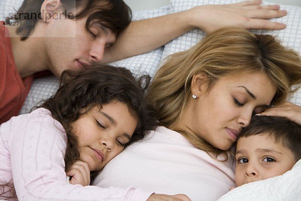 Eine Familie mit zwei Kindern  die im Bett schlafen.