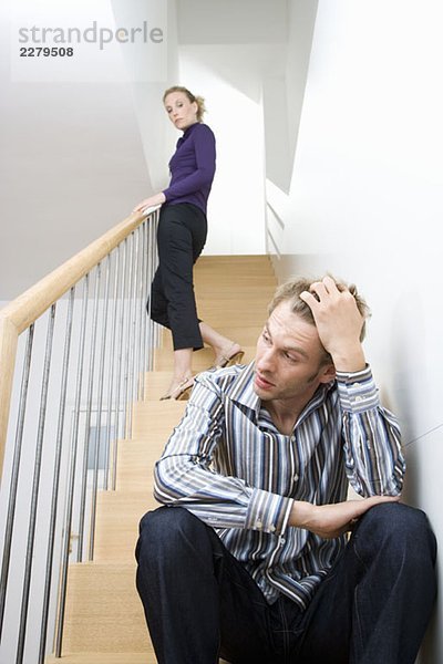 Ein mittleres erwachsenes Paar  das sich auf einer Treppe streitet.