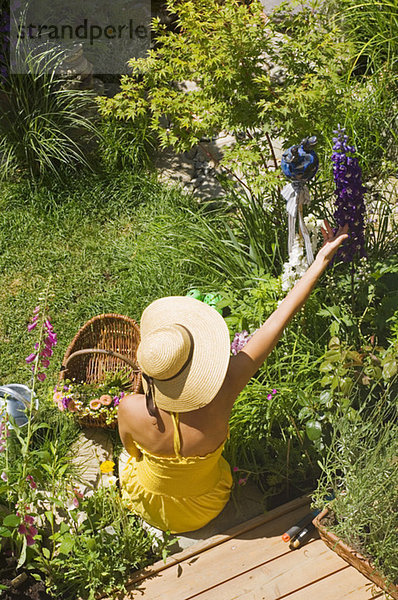 Frau mit Sonnenhut im Garten  Draufsicht
