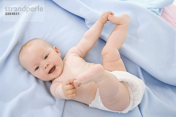 Baby Junge (6-9 Monate) auf dem Bett liegend  Zehen berührend