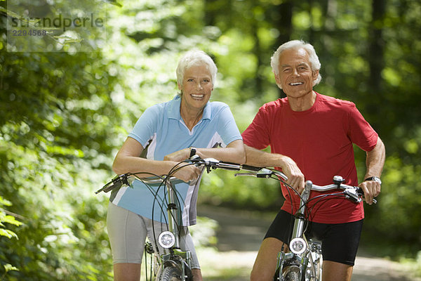Seniorenpaar mit Fahrrädern  lächelnd  Portrait
