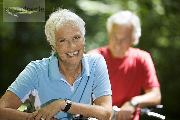 Seniorenpaar mit Fahrrädern  Frau lächelnd  Portrait