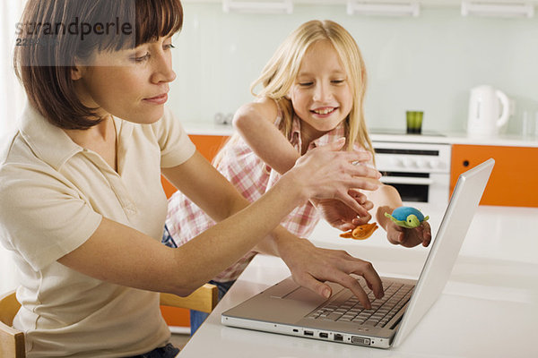 Mutter und Tochter (8-9) in der Küche  Mutter mit Laptop