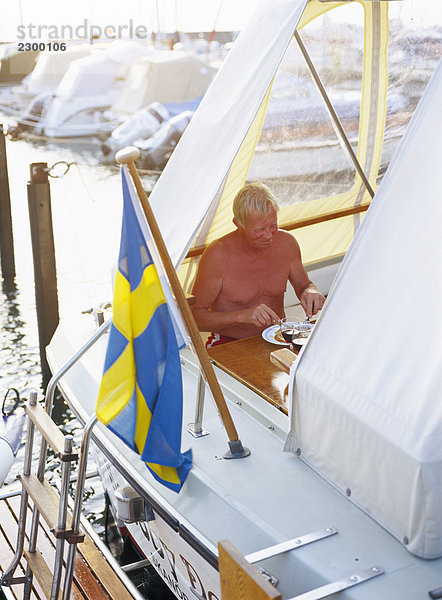 Ein Mann sitzt auf einem Motorboot und essen Abendessen