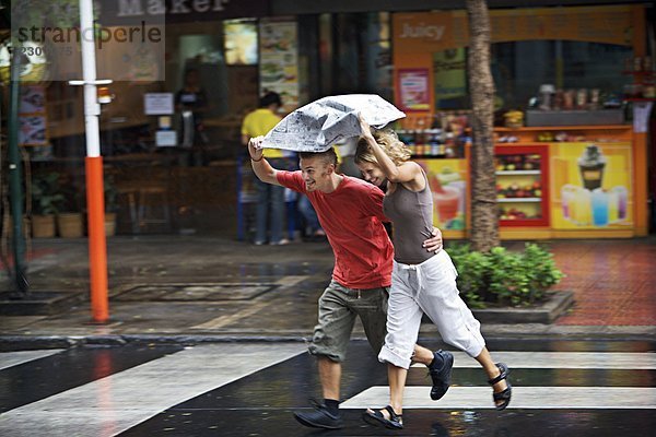 Ein skandinavischen Paar im Regen überqueren einer Straße Thailand