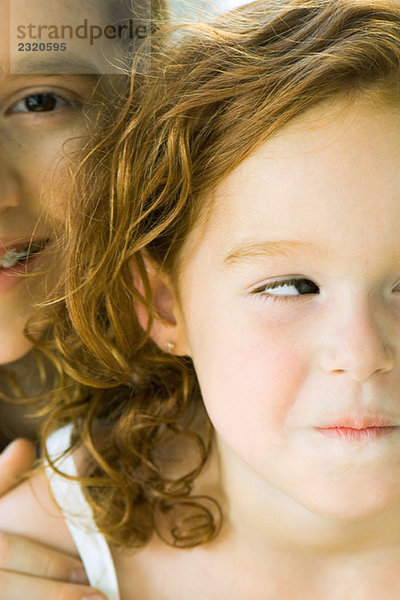 Junge blickt über die Schulter der Schwester in die Kamera  beide lächelnd  Ausschnittansicht