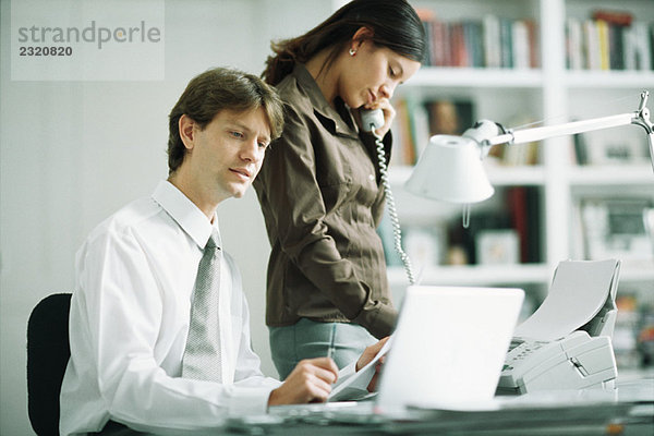 männliche und weibliche Kollegen am Schreibtisch  Mann mit Laptop  Frau mit Telefon