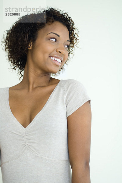 Junge Frau lächelt über die Schulter  Taille nach oben
