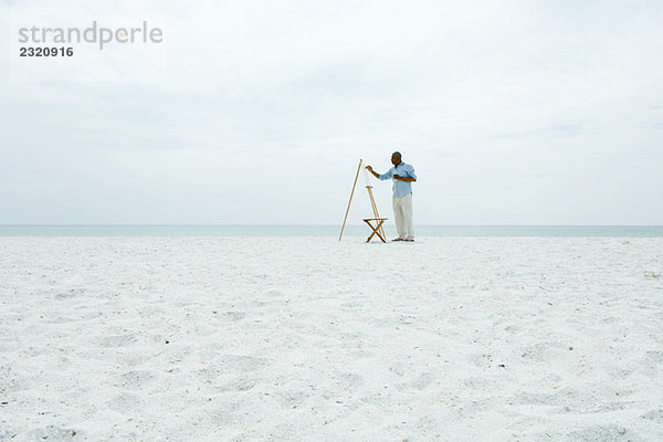 Männermalerei am Strand  Seitenansicht  in der Ferne