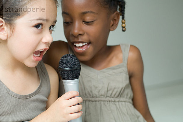 Zwei kleine Mädchen singen zusammen ins Mikrofon  Nahaufnahme