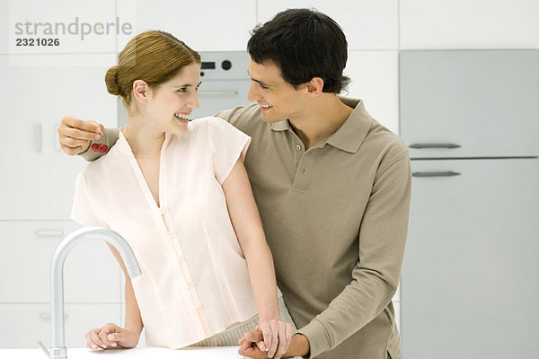 Paar hält sich in der Küche an den Händen  lächelt sich an  Mann hält Kirschen.