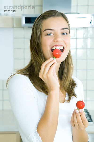 Junge Frau isst Rettich in der Küche  Portrait