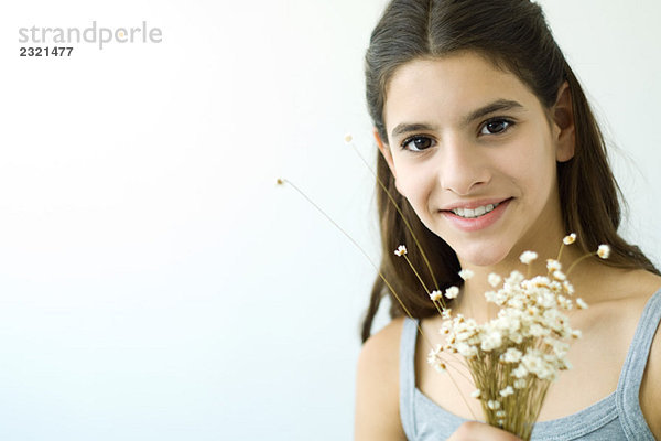 Teenagermädchen hält Blumenstrauß  lächelt in die Kamera  Portrait