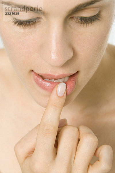 Frau hält Finger an Lippe  Nahaufnahme von Gesicht und Mund