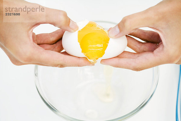 Frau knackt Ei in Rührschüssel  abgeschnittene Ansicht der Hände  Hochwinkelansicht