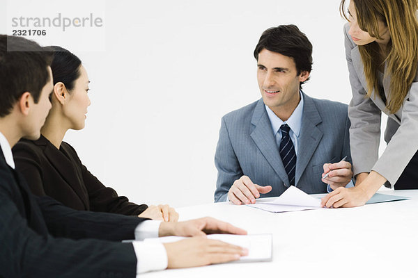 Geschäftspartner am Tisch sitzend  ein Mann unterschreibt Dokument