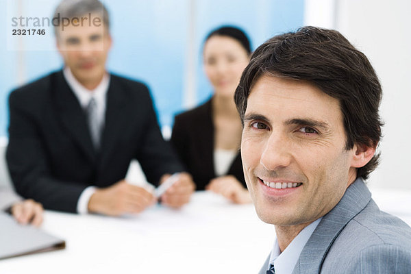 Geschäftsmann im Meeting  lächelnd vor der Kamera