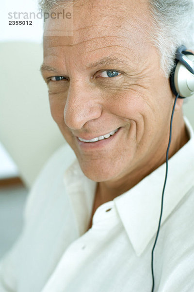 Erwachsener Mann hört Kopfhörer  lächelt in die Kamera  Nahaufnahme