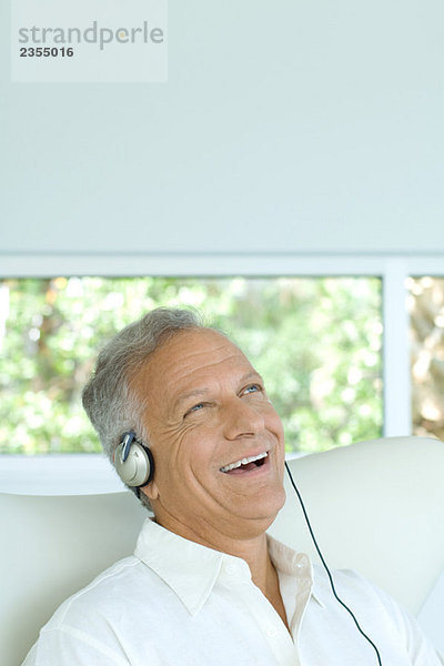 Erwachsener Mann hört Kopfhörer  lacht  schaut nach oben