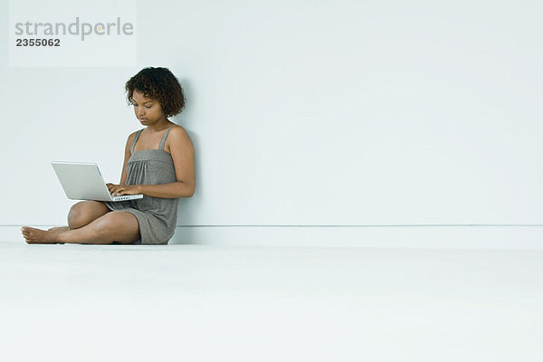 Junge Frau auf dem Boden sitzend  mit Laptop-Computer
