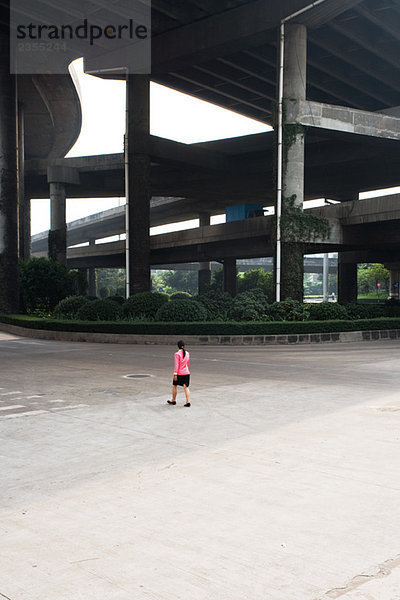 China  Guangzhou  Fußgängerin unter der Brücke  Rückansicht