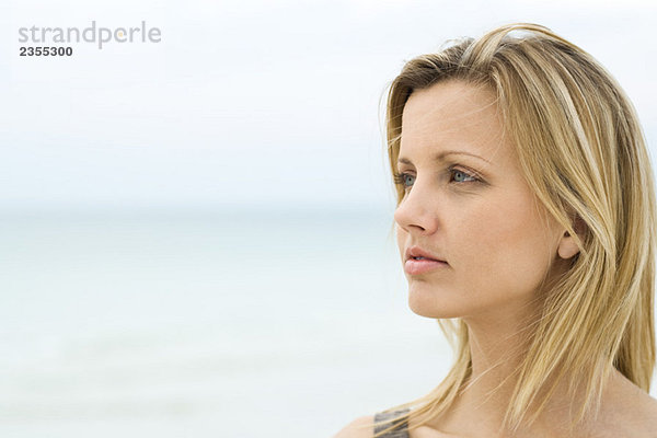 Blonde Frau schaut in die Ferne  Meer im Hintergrund  Kopf und Schultern