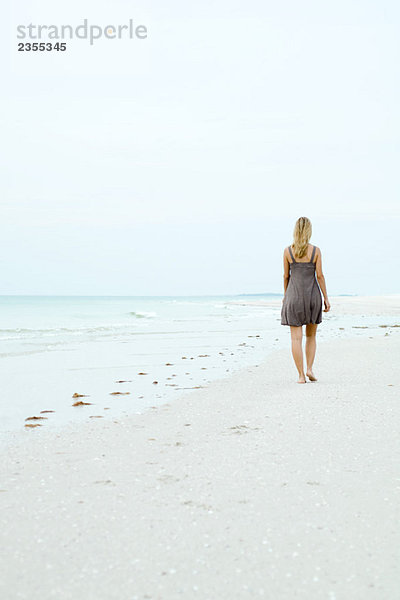 Frau im Sonnenkleid am Strand  Rückansicht