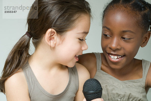 Zwei kleine Mädchen singen ins Mikrofon  Nahaufnahme