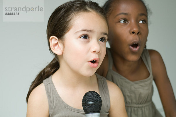 Zwei kleine Mädchen singen zusammen ins Mikrofon  Nahaufnahme