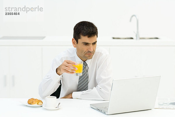 Mann beim Frühstück und mit Laptop