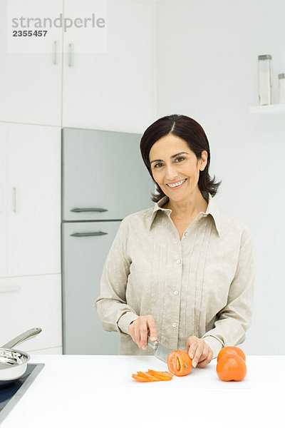 Frau beim Tomatenschneiden in der Küche