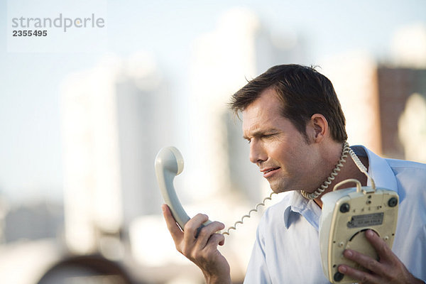 Mann wickelt Festnetz-Telefonkabel um den Hals  Blick auf den Hörer