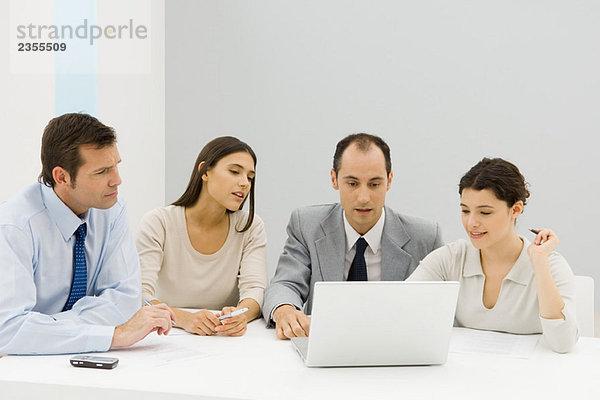 Team von Geschäftspartnern  die gemeinsam im Büro auf den Laptop schauen