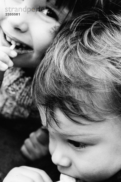 Zwei Geschwister essen Lollis  Mädchen lächelt vor der Kamera  Nahaufnahme