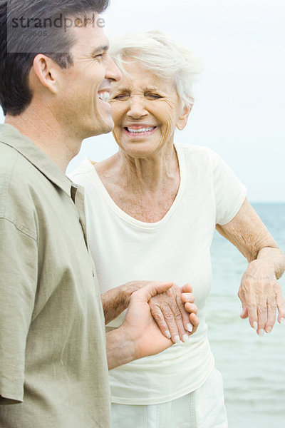 Seniorin und erwachsener Sohn  Händchen haltend  lachend  Augen geschlossen