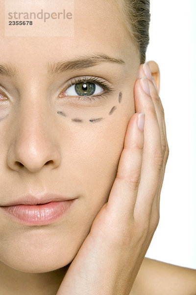 Frau mit plastischen Operationsmarkierungen unter dem Auge  Gesicht haltend  in die Kamera schauend  beschnitten