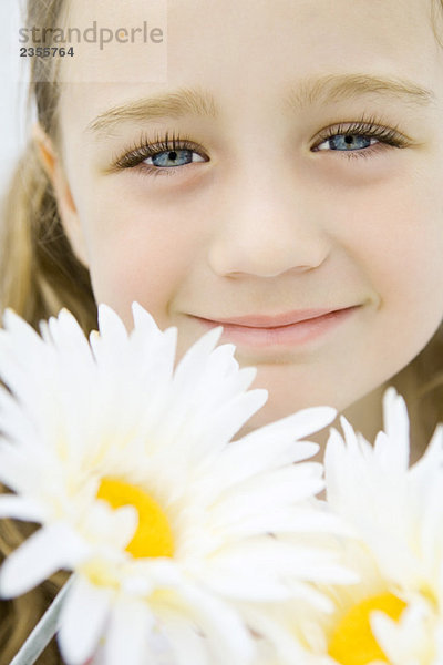 Kleines Mädchen mit Gerbera-Gänseblümchen  lächelnd vor der Kamera  Portrait