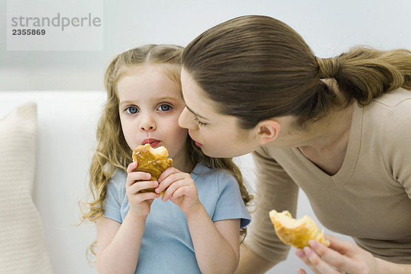 Mutter und kleines Mädchen essen Croissants  Mädchen schaut in die Kamera