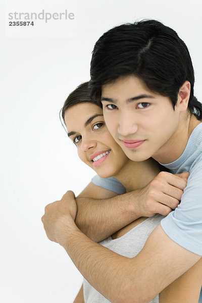 Junges Paar lächelnd vor der Kamera  umarmend  Porträt